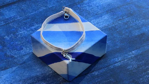 Bracelet en tissu blanc avec rayures bleues orné d'une breloque en forme d’arête