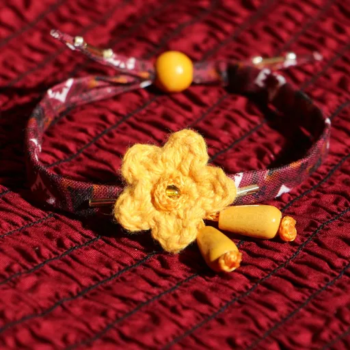 Bracelet en coton alliant tissu bordeaux avec motifs, fleur ocre en crochet orné