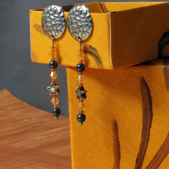 Paire de boucles d’oreilles composées d'une base ronde en acier martelé et d’un 