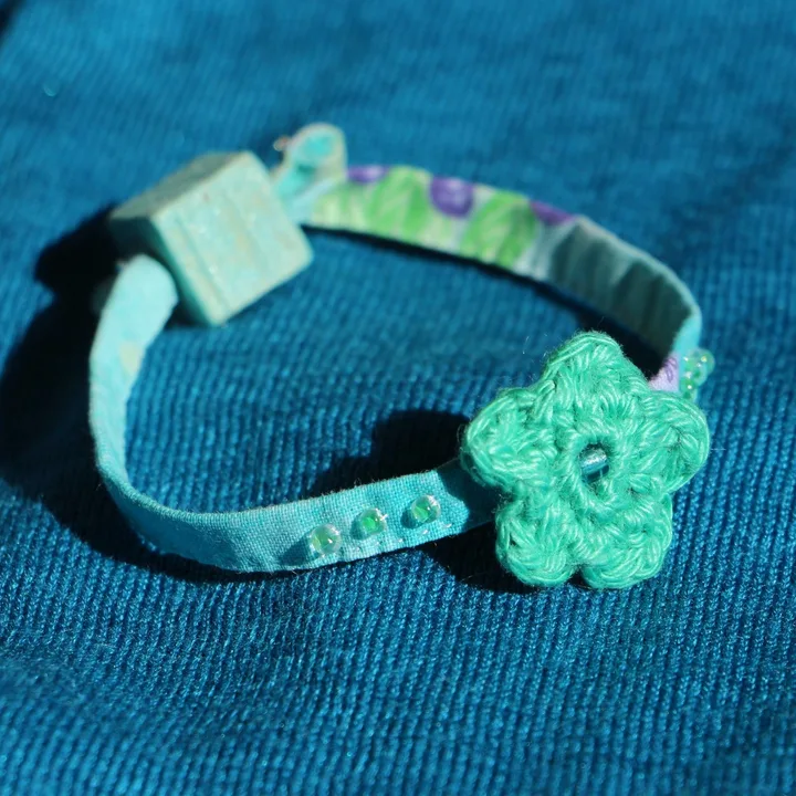 Bracelet en tissu turquoise orné de perles de rocaille et d'une fleur au crochet